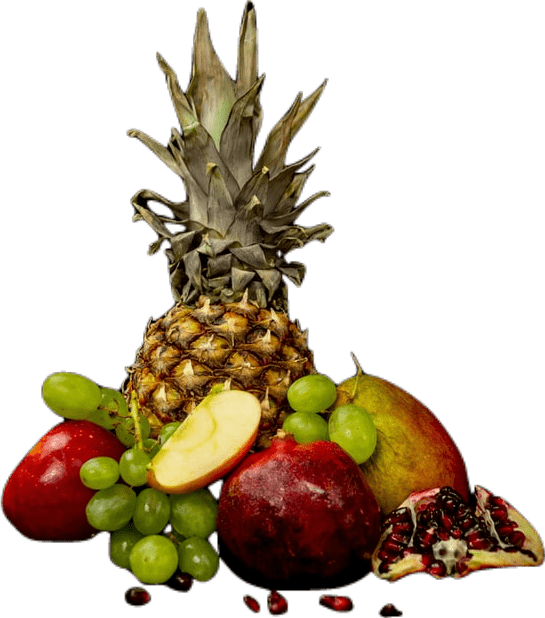A pile of assorted fruit, including a pineapple, pomegranate, apple, grapes, and mangoes.
