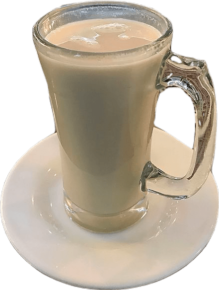 A tall glass mug full of milky white horchata beverage on a white saucer.