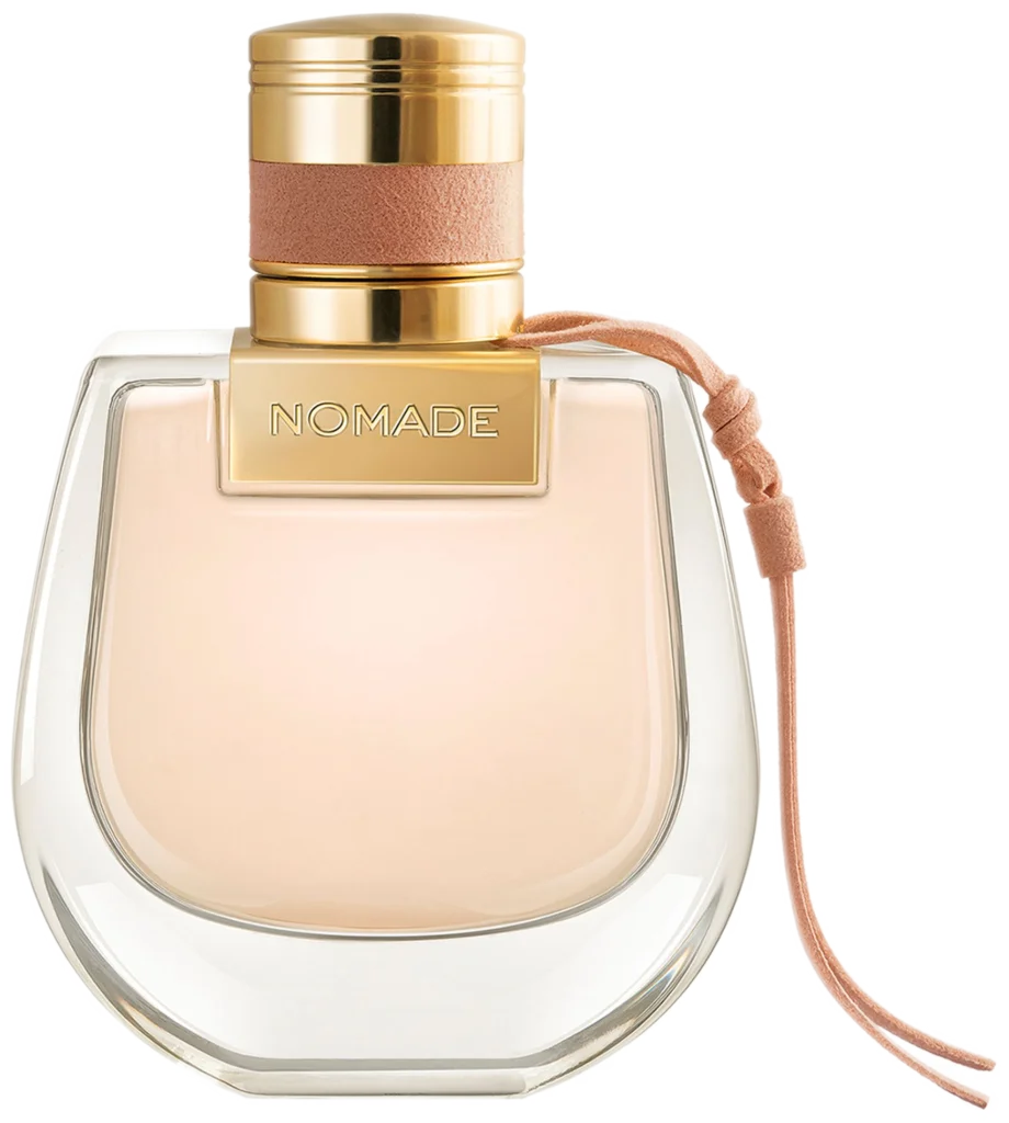 Bottle of Chloe's Nomade Eau de Toilette, shaped like the brand's iconic saddle bag and filled with light-peach-color liquid.
