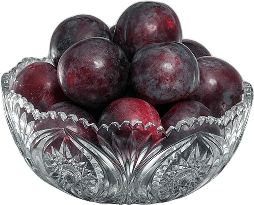 An ornate crystal glass bowl filled with round, dark reddish black plums.