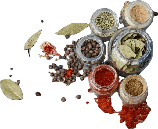 A number of glass jars filled with various colored spices, which are also spilled and scattered around the jars.