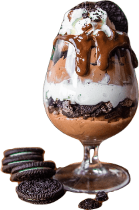 A cognac glass filled with layers of gelato, Oreo sandwich cookies, a chocolatey sauce and a large dollop of whipped cream.