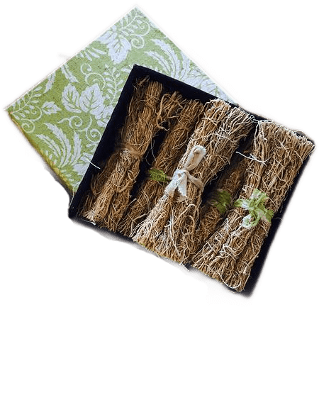 A green and white origami paper box containing many small bundles of dried vetiver grass tied with strips of cloth and twine.
