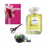 Ask Sophie: Should I Tell My Friend I Regifted Her Gift? Collage of a bottle of yellow-green Chanel No. 19, a pink wrapped gift box, a pair of scissors, and a plant in a lightbulb.