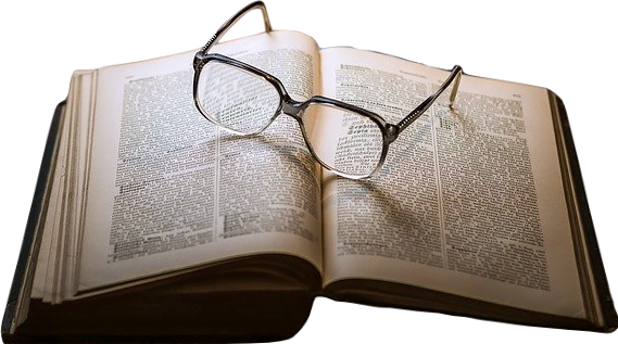 A leather-bound book with yellowing pages flipped open to a page near the end, with a pair of glasses sitting on top of it.