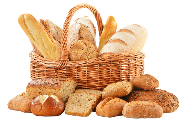 A woven basket filled with and surrounded with a number of different kinds of freshly-baked bread.
