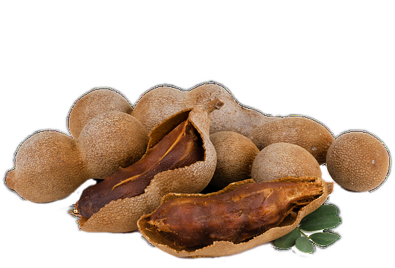 A pile of brown tamarind fruit in their hard, peapod-like shells with some green leaves.