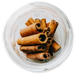 A small clear glass filled with rich, deep brown dried cinnamon spice sticks.