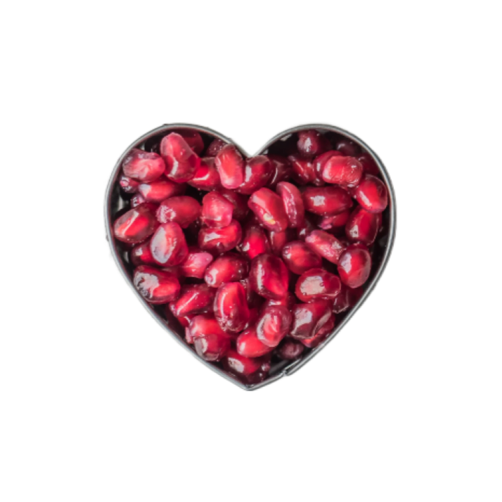 A metal heart-shaped tin filled with bright cerise reddish-pink pomegranate arils.