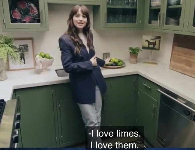 Screenshot of a home-selling video by actress Dakota Johnson. She stands in her green-themed kitchen, saying, "I love limes."