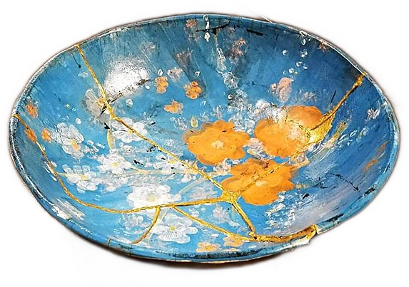 A pale blue hand-painted plate with yellow flowers that has been broken and repaired with gold laquer in the kintsugi style.