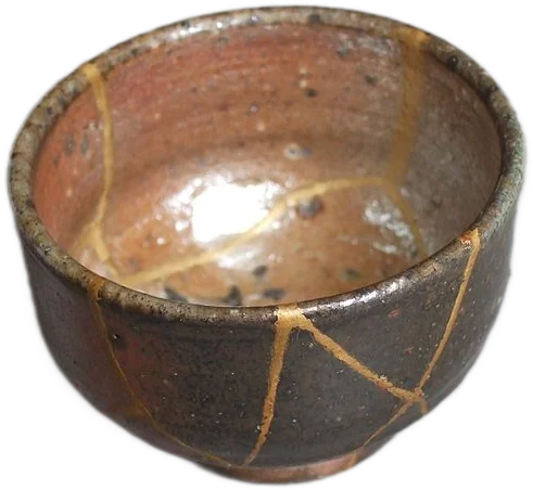 A brown bowl with cracks that have been repaired with gold lacquer in the kintsugi style.