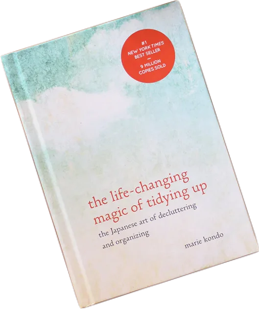 Book cover of The Life-Changing Magic of Tidying Up by Marie Kondo, printed with pale blue and pink sky.