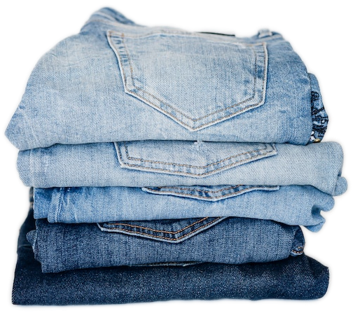 A stack of five neatly folded pairs of blue jeans in varying color washes.