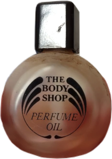 A faded round vintage bottle of perfume oil from the Body Shop with a rectangular cap.